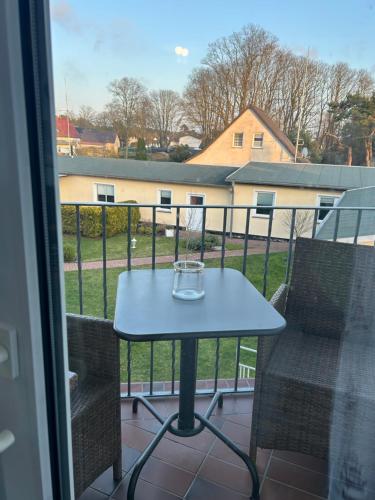 a table and chairs on a balcony with a window at Strandkojen in Trassenheide