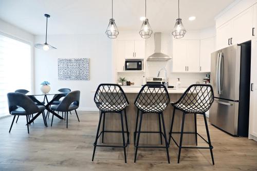 La cuisine est équipée d'une table, de chaises et d'un réfrigérateur. dans l'établissement Stylish Home with 3 King Beds,Garage,Disney+, à Edmonton