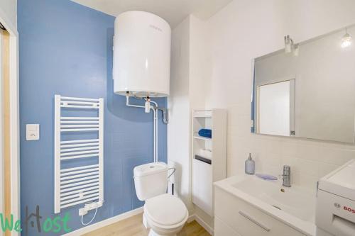 La salle de bains est pourvue de toilettes blanches et d'un mur bleu. dans l'établissement Scribe bleu - Centre ville - moderne et calme, à Nantes