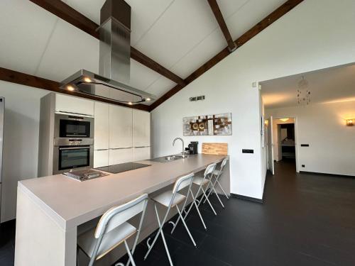 a kitchen with a large island with bar stools at Groot vakantiehuis nabij Amsterdam inclusief jacuzzi in Zeewolde