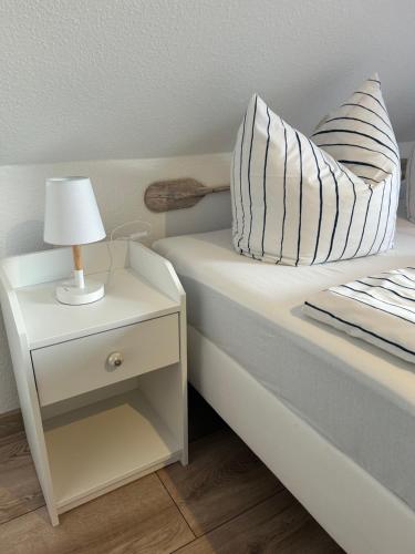 a bed with a nightstand with a lamp on it at Strandkojen in Trassenheide