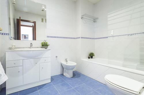 a white bathroom with a sink and a toilet at Apartamento EL MIRADOR, recepción 24 h, piscina, wifi y parking interior in Bormujos