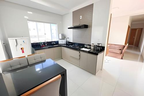 uma grande cozinha branca com um balcão preto em M203- Apartamento c/ Suíte Completo Patos de Minas em Patos de Minas
