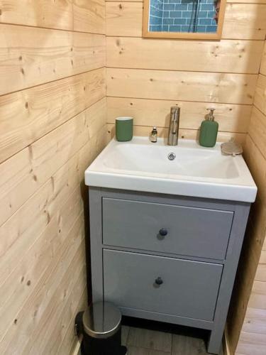 La salle de bains est pourvue d'un lavabo blanc et d'un mur en bois. dans l'établissement Welcoming new architects house with jacuzzi, à Hourtin