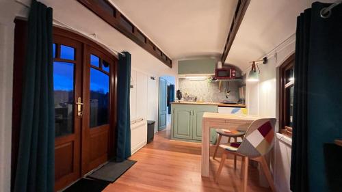 a small kitchen with a table and a door at La roulotte de Fichous in Fichous-Riumayou