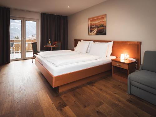 una camera d'albergo con un grande letto e una sedia di Hotel Panorama a Rablà