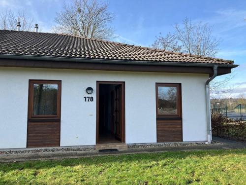 une petite maison blanche avec une porte dans une cour dans l'établissement Ferienhaus Lena am Silbersee, à Frielendorf