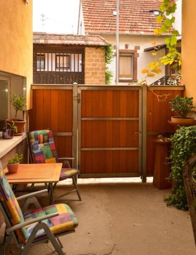 a patio with a wooden fence and a table and chairs at Unter den Reben in Niederkirchen bei Deidesheim
