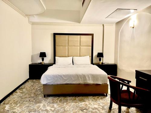 a bedroom with a bed and two tables and a chair at Al-Sadier Place Hotel & Restaurant in Baghdad