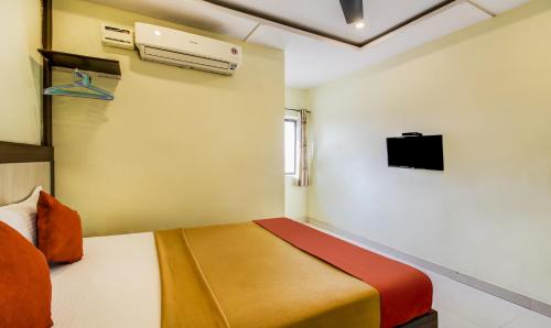 a bedroom with a bed and a tv on the wall at Hotel Neem Tree Hyderabad Airport in Shamshabad