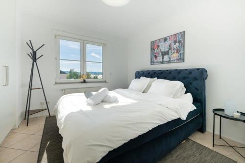Un dormitorio con una cama azul con sábanas blancas y una ventana en Modern Penthouse in Sanem, en Sanem