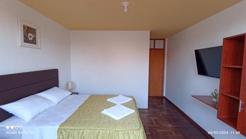 a bedroom with a bed and a flat screen tv at Montecristo Hotel in Tacna