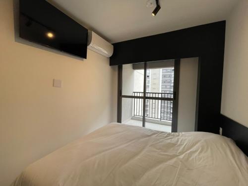 a bedroom with a white bed and a window at Studio completo luxo novo in Sao Paulo