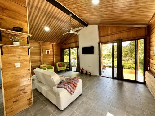 sala de estar con sofá blanco y paredes de madera en Romantic Private Cabin in the Forest, Bungalows Tulipanes, en San Ramón