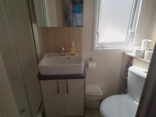 a small bathroom with a sink and a toilet at Seasalter Cosy Caravan, in Seasalter