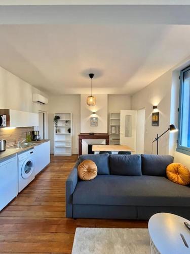 un salon avec un canapé bleu et une cuisine dans l'établissement Le Printemps * Bel appartement climatisé * Hypercentre, à Toulouse