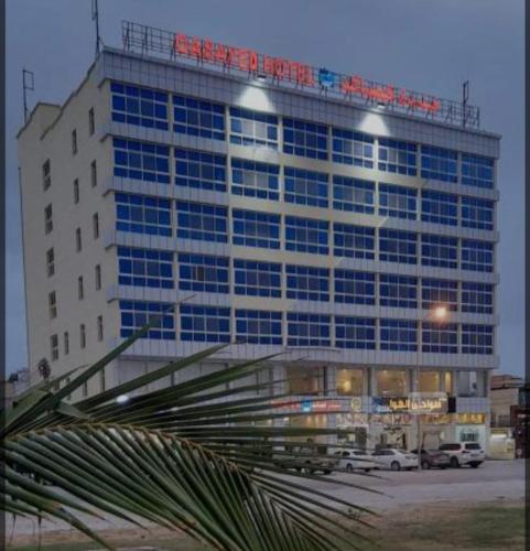 a large building with a sign on the top of it at Qasayed Hotel Salalah, فندق قصائد صلالة in Salalah