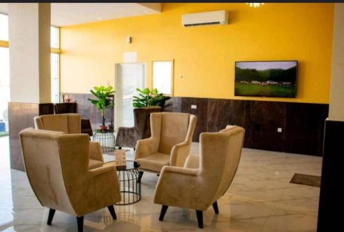une salle d'attente avec des chaises et une télévision sur un mur jaune dans l'établissement قصائد, à Salalah
