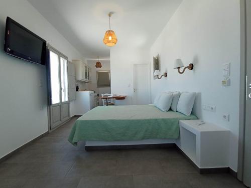 a white bedroom with a bed and a television at Seascape, apartment with sea view 1 in Áno Meriá