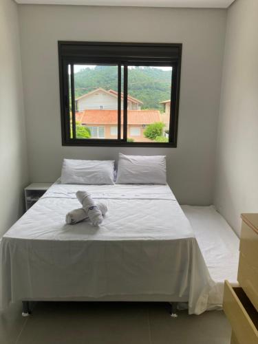 a bedroom with a white bed with a window at Conchas das Caravelas in Governador Celso Ramos