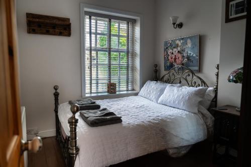Schlafzimmer mit einem Bett mit weißer Bettwäsche und einem Fenster in der Unterkunft The Little Hideaway - Historic Gem off Haworth Main Street in Haworth