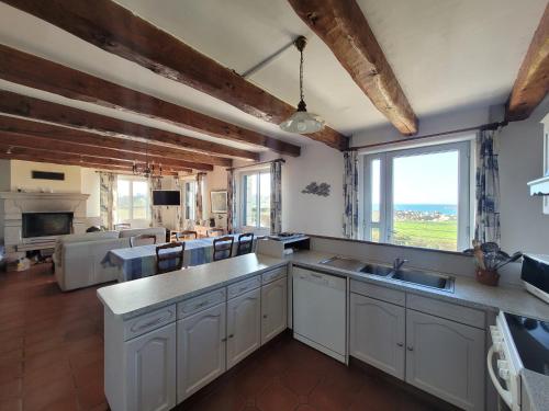 une grande cuisine avec des placards blancs et une grande fenêtre dans l'établissement Maison reposante face à la mer avec accès plage, à Plouescat