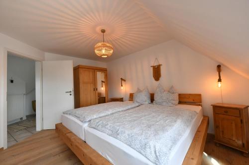 a bedroom with a large white bed with a chandelier at Ferienwohnung am Altenlinderstall in Lindlar