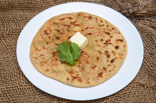 a white plate with a tortilla with a pat of cheese at Collection O Pratik Inn in Chinhat
