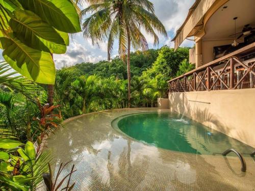 a swimming pool in front of a house with trees at Casa Maka - Stunning Oceanfront Villa in Santa Cruz Huatulco