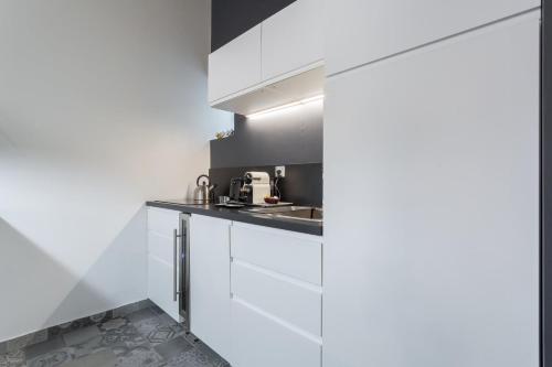 a kitchen with white cabinets and a sink at La Suite Boissac - Cœur de Lyon - Bellecour in Lyon