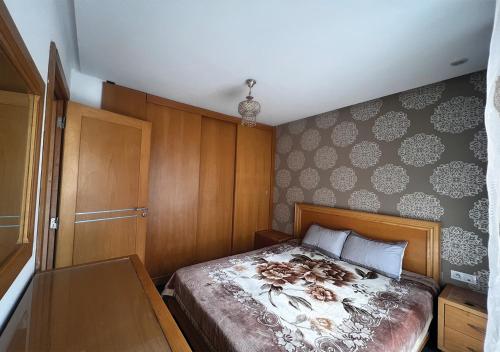 sypialnia z łóżkiem z drewnianym zagłówkiem w obiekcie Apartment in Sousse​ w Susie