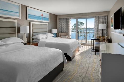パナマ・シティ・ビーチにあるBluegreen's Bayside Resort and Spa at Panama City Beachのベッド2台とバルコニー付きのホテルの部屋