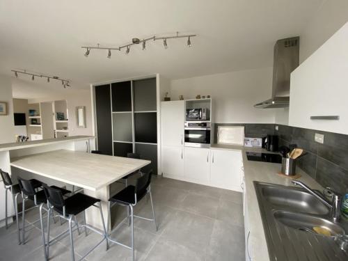 une cuisine avec une table, des chaises et un évier dans l'établissement Maison vue mer - 2 à 10 personnes, à Locquirec