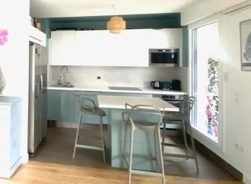 - une cuisine avec un comptoir bleu et des tabourets dans l'établissement Appartement familial de standing, à Boulogne-Billancourt