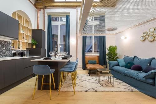 a living room with a blue couch and a kitchen at Cocon Cordeliers / 4 voyageurs in Lyon