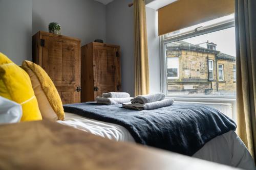 1 dormitorio con 1 cama y ventana con toallas en Sun Street Cottage - with log burner, jet bath and Summerhouse, en Haworth