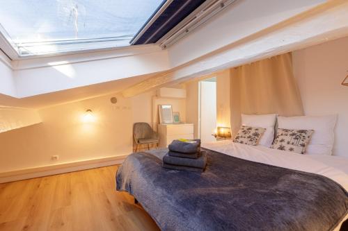une chambre avec un grand lit avec une lucarne dans l'établissement La Maison 44 - Duplex T3 - Clim, calme, Via Rhôna, à Montélimar