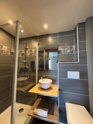 uma casa de banho com um lavatório e uma cabina de duche em vidro. em Hôtel-Restaurant Le Hauteville em Hauteville-Lompnes