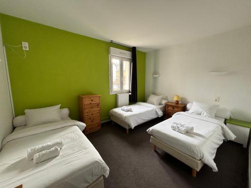 Habitación con 2 camas y pared verde. en Hôtel-Restaurant Le Hauteville en Hauteville-Lompnes