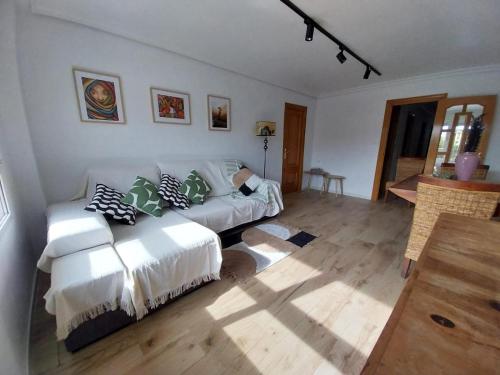 Apartamento Thematic OyM في بليانة: غرفة معيشة مع أريكة بيضاء مع وسائد عليها