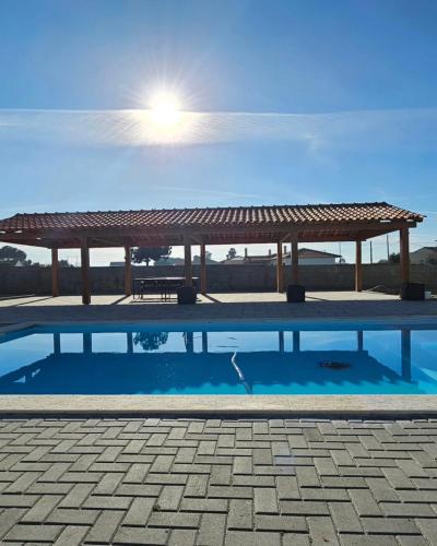 a pavilion with a picnic table and a swimming pool at Quinta Marinhais Privada no Ribatejo com Piscina, BBQ e Animais, Perto de Lisboa in Marinhais