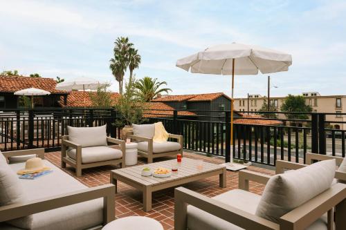 a patio with chairs and tables and an umbrella at Sonder Woods Cove in Laguna Beach