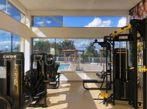 a gym with several tread machines and a large window at Quarto em casa com lazer completo in Indaiatuba