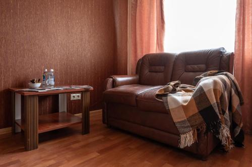 a living room with a brown leather couch and a table at готель Моряк in Chornomorsk
