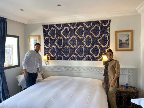 two men standing next to a bed in a room at Dar Nour in Tangier