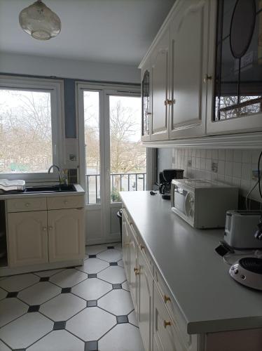 Il comprend une cuisine avec des placards blancs et du carrelage blanc. dans l'établissement Joli appartement type 5 en centre ville, à Châteauroux