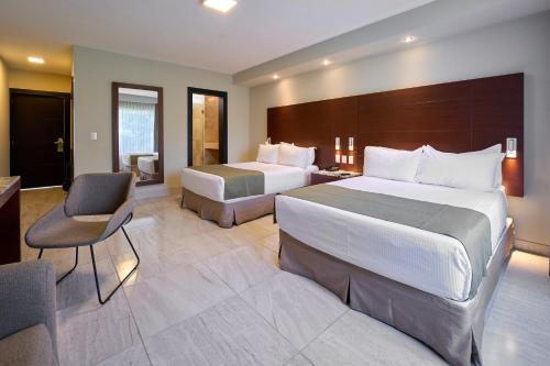 a hotel room with two beds and a desk at Hotel Estancia Business Class in Guadalajara