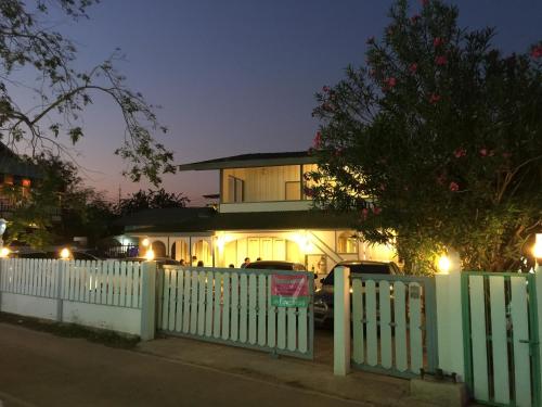 a white fence in front of a house with lights at Baan Songsri in Amphawa