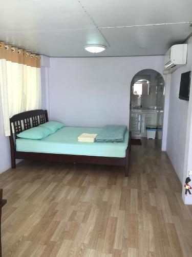 ein Schlafzimmer mit einem Bett in einem Zimmer mit Holzboden in der Unterkunft Baan Songsri in Amphawa