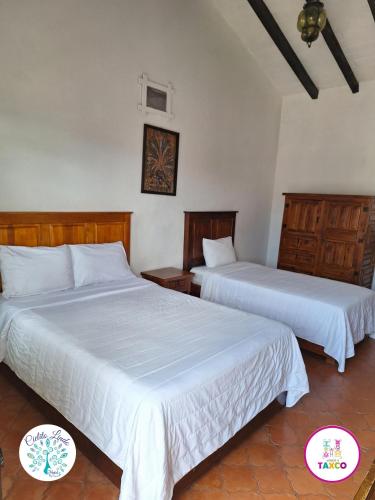 two beds in a room with white sheets at Hotel Cielito Lindo, Taxco in Taxco de Alarcón